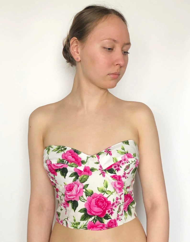May include: A strapless white and pink floral print corset top.