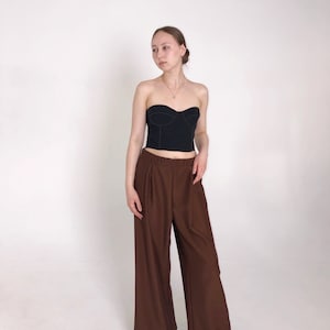 May include: A black strapless top with a sweetheart neckline and a brown wide-leg pant.