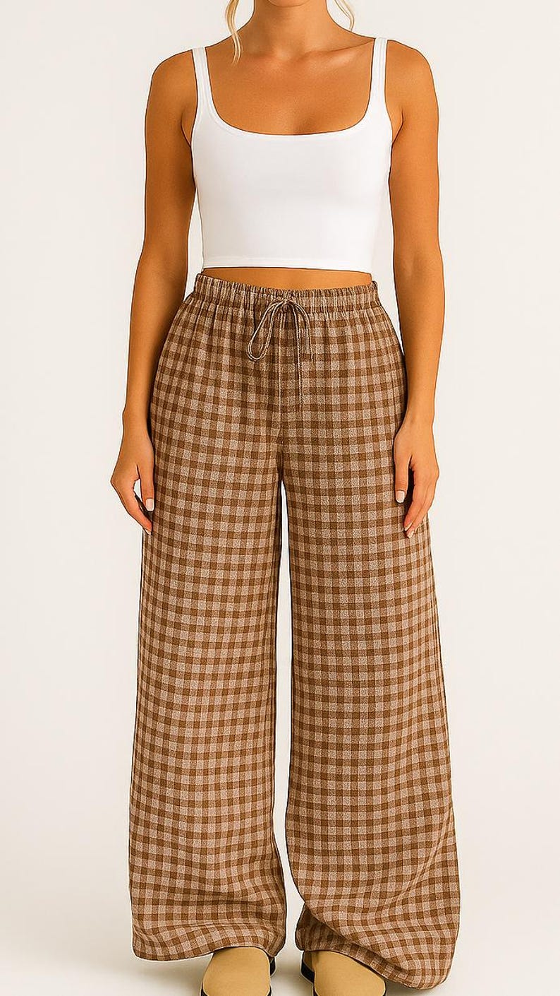 May include: A white crop top paired with brown and tan plaid wide-leg pants. The pants have a drawstring waist. The outfit is casual and comfortable, suitable for everyday wear. The pants have a classic gingham pattern.