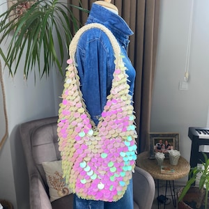 May include: A pink and white iridescent sequin shoulder bag with a crocheted strap.