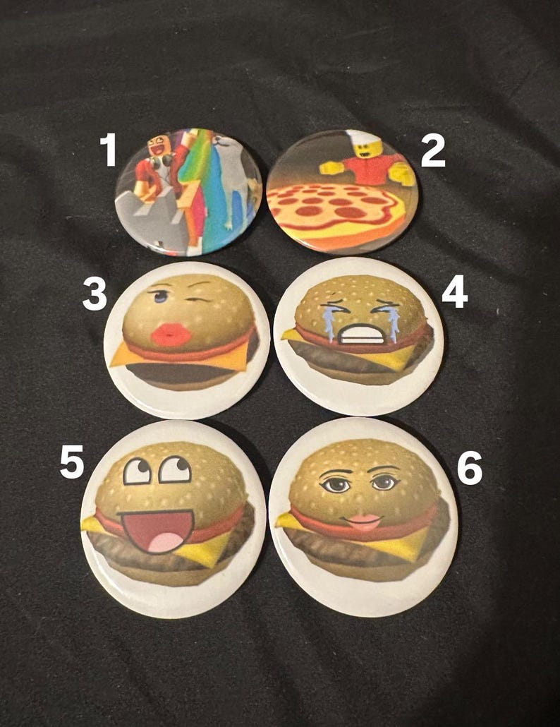 Op de afbeelding: Zes ronde knoppen met verschillende afbeeldingen. De eerste knop heeft een cartoonafbeelding van twee mensen in een videogame. De tweede knop heeft een cartoonafbeelding van een pizza. De derde, vierde, vijfde en zesde knop hebben cartoonafbeeldingen van hamburgers met verschillende gezichtsuitdrukkingen.