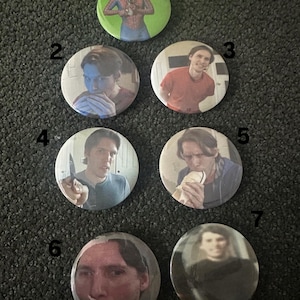 May include: Nine round button pins with different images. The buttons are white with a silver rim. The images include a man in a red shirt, a man in a blue shirt, a man in a green shirt, a man in a black shirt, a man in a white shirt, a man in a gray shirt, a man in a red shirt, a man in a black shirt, and a man in a green shirt.