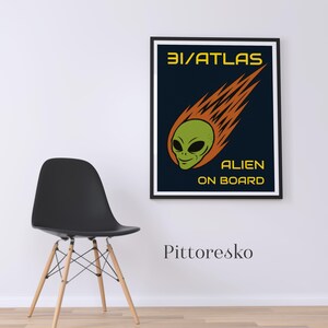 Può includere: Poster con cornice nera con la scritta "3I/ATLAS ALIEN ON BOARD" e un'illustrazione di una testa di alieno verde con fiamme arancioni. Il poster è appeso a una parete bianca accanto a una sedia nera.