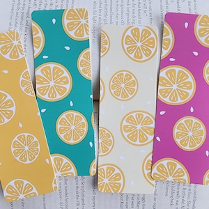 May include: Four lemon-themed bookmarks with different background colors: yellow, teal, cream, and pink. Each bookmark features a repeating pattern of lemon slices and white seeds.