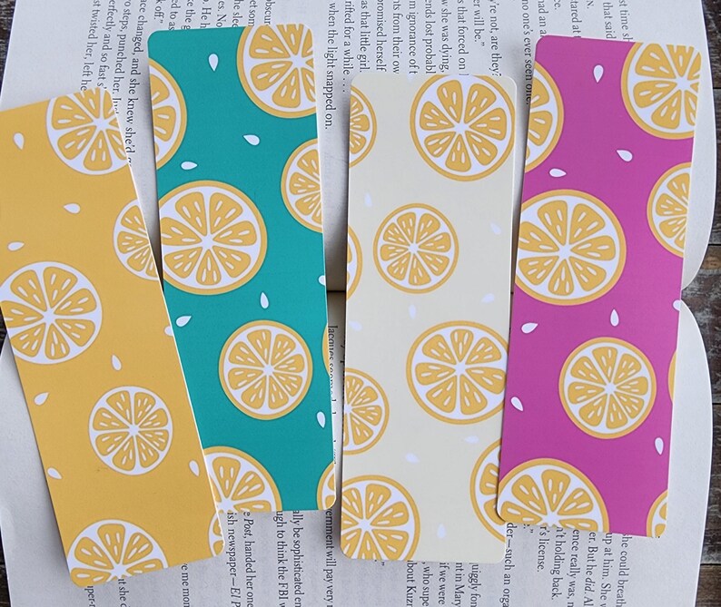 May include: Four lemon-themed bookmarks with different background colors: yellow, teal, cream, and pink. Each bookmark features a repeating pattern of lemon slices and white seeds.