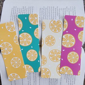 May include: Four bookmarks with a lemon slice pattern. The bookmarks are in yellow, teal, cream, and pink. The text on the cream bookmark reads "They're not, are they?" "They never will be."