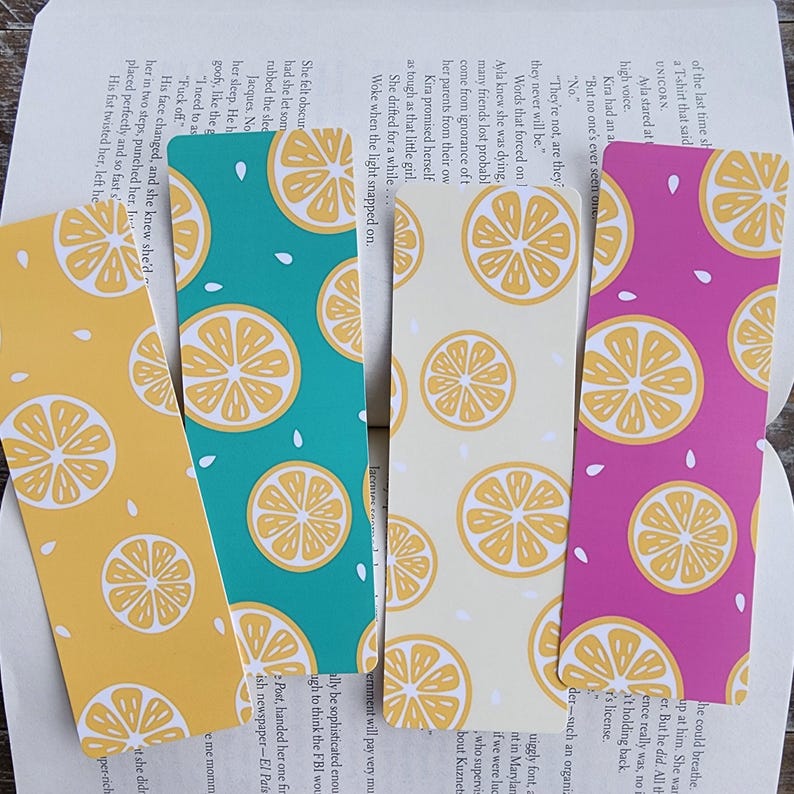 May include: Four bookmarks with a lemon slice pattern. The bookmarks are in yellow, teal, cream, and pink. The text on the cream bookmark reads "They're not, are they?" "They never will be."