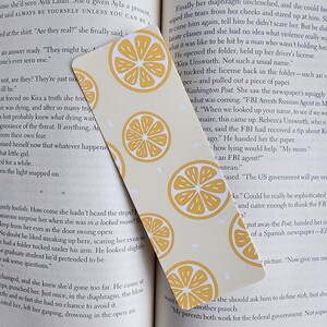 May include: A yellow and white bookmark with a lemon pattern. The bookmark has the text "FBI Arrests Russian Agent in Moscow" printed on it.