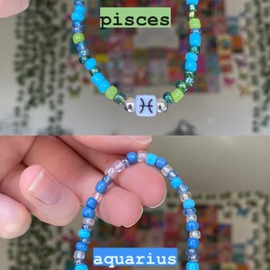 May include: Two beaded bracelets, one with green, blue, and silver beads and the word "pisces", and the other with blue and clear beads and the word "aquarius". Each bracelet has a white cube bead with a zodiac symbol.