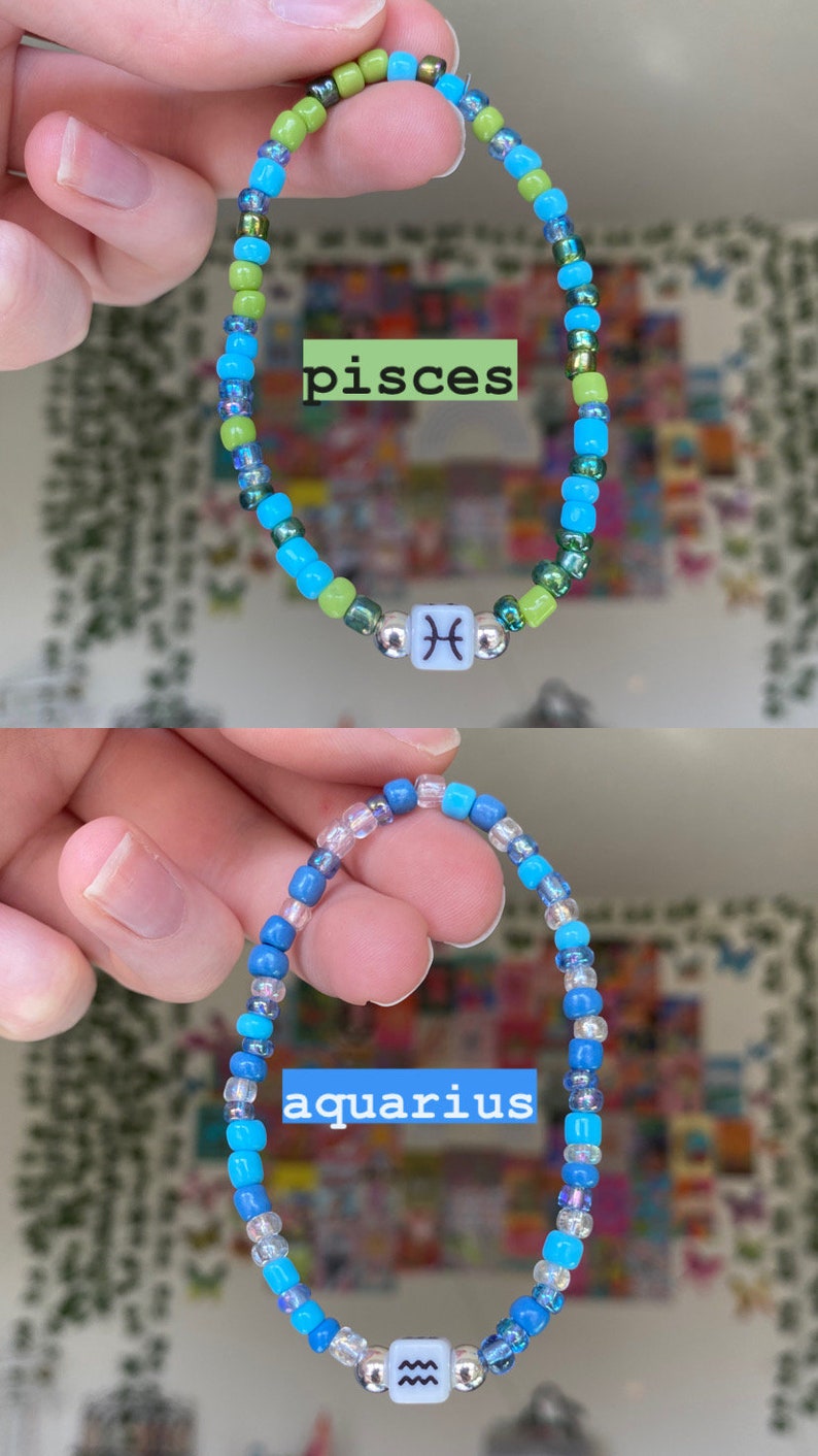 May include: Two beaded bracelets, one with green, blue, and silver beads and the word "pisces", and the other with blue and clear beads and the word "aquarius". Each bracelet has a white cube bead with a zodiac symbol.