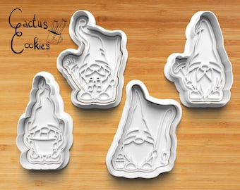 May include: Four white plastic gnome-shaped cookie cutters on a wooden cutting board. The cutters feature different gnome designs, including one with a watering can and another with a bucket. The text "Cactus Cookies" is in the upper left corner.