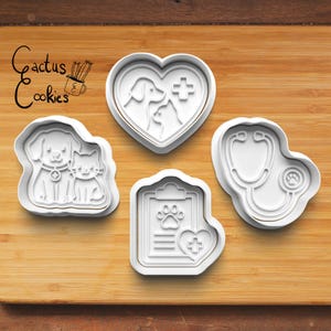 May include: Four white plastic cookie cutters featuring veterinary themes, including a heart with a dog and cat, a dog and cat pair, a medical clipboard with a paw print, and a stethoscope. The text Cactus Cookies is visible in the upper left corner.