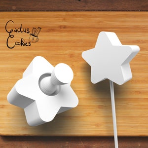 Puede incluir: Dos cortadores de galletas en forma de estrella de plástico blanco. Un cortador es plano y el otro es un cortador de émbolo con un mango redondo.