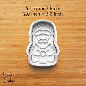 Puede incluir: Cortador de galletas de pl&aacute;stico blanco con forma de figura de Pap&aacute; Noel. El cortador mide 5,1 cm de ancho y 7,6 cm de alto. El cortador tiene un dise&ntilde;o detallado de la cara, el sombrero y el atuendo de Pap&aacute; Noel. El texto "Cactus Cookies" est&aacute; en la esquina inferior izquierda.