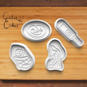 Pode incluir: Quatro cortadores de biscoitos de plástico branco em forma de mulher grávida, bebê em um envoltório, bebê no útero e teste de gravidez. Os cortadores de biscoitos estão em uma superfície de madeira.