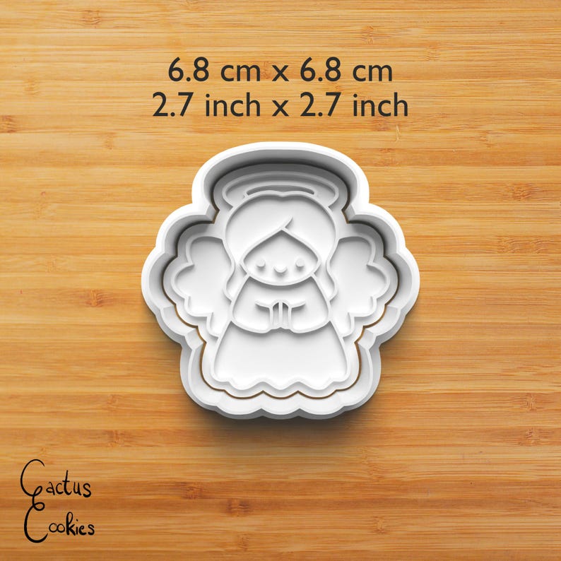 Puede incluir: Un cortador de galletas de pl&aacute;stico blanco con forma de &aacute;ngel, de 6,8 cm por 6,8 cm. El cortador presenta un &aacute;ngel con alas, un halo y las manos juntas. El texto "6.8 cm x 6.8 cm" y "2.7 inch x 2.7 inch" es visible.