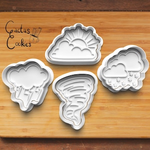 May include: Four white plastic cookie cutters shaped like weather elements: a sun behind a cloud, a cloud with snowflakes, a cloud with rain, and a tornado.
