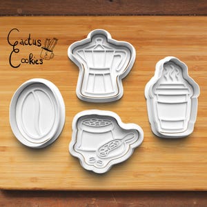 Puede incluir: Cuatro cortadores de galletas de plástico blanco con formas de café: un grano de café, una cafetera italiana, una taza de café para llevar y una bolsa de granos de café con una cuchara. Las palabras "Cactus Cookies" están en la esquina superior izquierda.