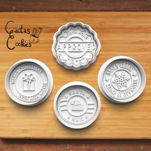 May include: Four white plastic cookie cutters with Christmas themes. The cutters are shaped like circles and feature the text "Merry Christmas Happy New Year", "North Pole Approved Air Mail", "Santa Claus Stamp of Approval", and "Santa Air Mail".