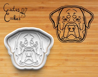 Könnte beinhalten: Ein weißer Plastik-Ausstecher in Form eines Rottweiler-Hundekopfes. Der Ausstecher liegt auf einem Holzbrett. Der Text "Cactus Cookies" ist in der oberen linken Ecke des Bildes sichtbar.