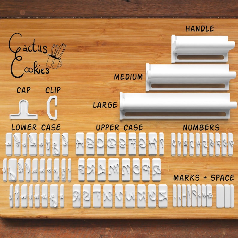May include: A set of white plastic cookie cutters and stamps, including upper and lower case letters, numbers, and punctuation marks. The set includes handles in three sizes: large, medium, and small. The logo "Cactus Cookies" is visible.