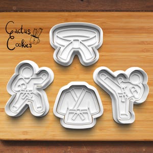 Könnte beinhalten: Eine Sammlung weißer Ausstecher aus Kunststoff in Karate-Designs. Das Set enthält einen Karate-Gürtel, eine Karate-Uniform und zwei Figuren in Karate-Posen. Der Text "Cactus Cookies" befindet sich in der oberen linken Ecke.