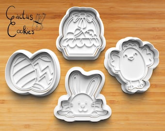 May include: Four white plastic cookie cutters shaped like an Easter basket with a bow, a bunny rabbit, a chick, and two Easter eggs. The cutters are on a wooden surface.