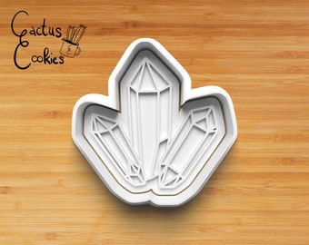 Könnte beinhalten: Ein weißer Ausstecher in Form von drei Kristallen. Der Ausstecher hat ein detailliertes Design mit scharfen Winkeln und Linien. Der Hintergrund ist eine hellbraune Holzoberfläche. Der Text "Cactus Cookies" befindet sich in der oberen linken Ecke.