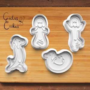May include: Four white plastic cookie cutters shaped like dogs in different yoga poses on a wooden cutting board. The text "Cactus Cookies" is written in black on the board.