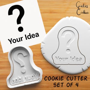 May include: Set of four white plastic cookie cutters shaped like a question mark with the text "Your Idea" underneath. The cookie cutters are on a wooden surface.
