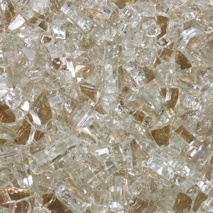 May include: A close-up view of a pile of clear glass fire pit rocks. The rocks are various sizes and shapes, with a slight iridescent sheen.