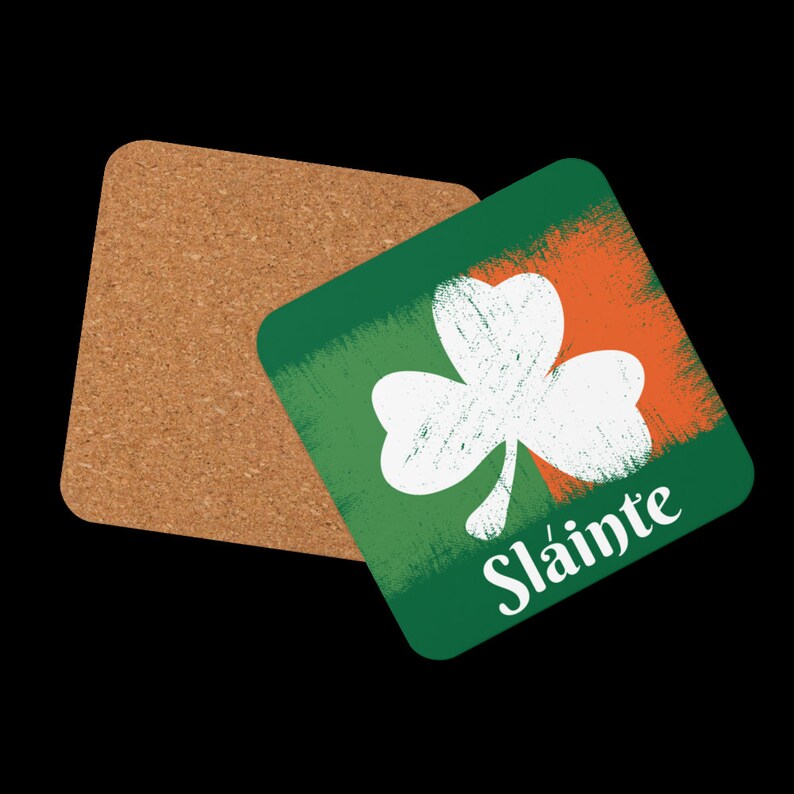 Puede incluir: Un posavasos cuadrado verde y naranja con un tr&eacute;bol blanco y el texto "Sl&aacute;inte" en blanco.