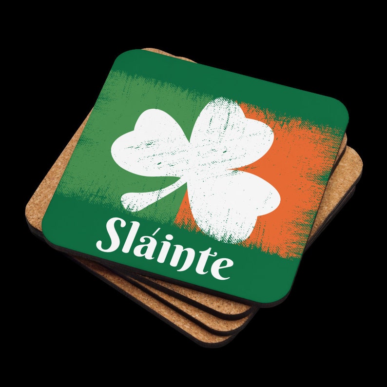 Puede incluir: Juego de cuatro posavasos verdes y naranjas con un tr&eacute;bol blanco y la palabra "Sl&aacute;inte" en letras blancas.