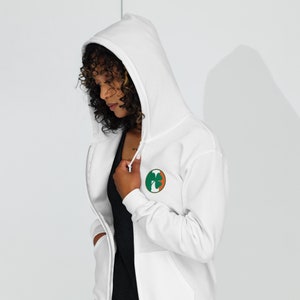 May include: White zip-up hoodie with a green shamrock design on the left chest.