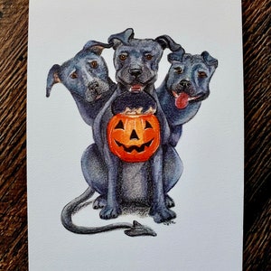 May include: A watercolor illustration of a three-headed black dog holding a jack-o'-lantern. The dog has a tail with a pointed end.