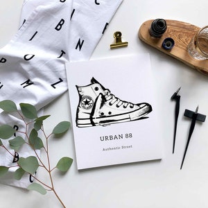 May include: A black and white illustration of a white sneaker with black laces and a black star logo. The illustration is on a white card with the text "URBAN 88 Authentic Street".