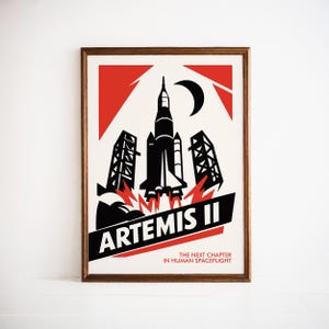May include: Framed poster featuring a black and red graphic of a rocket launching into space. The poster includes the text "Artemis II" and "The Next Chapter in Human Spaceflight". The design is set against a white background.