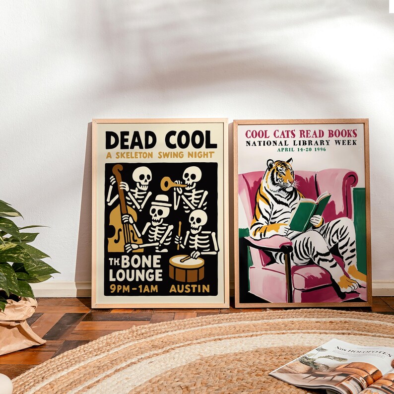 K&ouml;nnte beinhalten: Zwei gerahmte Kunstdrucke. Der linke Druck zeigt "DEAD COOL" mit Skelettmusikern. Der rechte Druck zeigt "COOL CATS READ BOOKS" mit einem lesenden Tiger. Beide Drucke haben einen Holzrahmen und sind auf hellem Hintergrund.