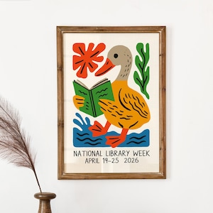 May include: A framed art print featuring a whimsical illustration of a duck reading a book. The duck is yellow and gray, with an orange beak and feet, standing in blue water. The print includes the text "NATIONAL LIBRARY WEEK APRIL 19-25 2026."