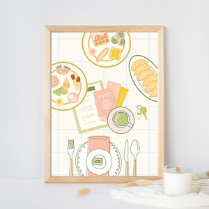 May include: A framed illustration of a table setting with a variety of pastries, a cup of tea, a passport, and keys. The table is set with a pink napkin, a fork, a knife, and a spoon. The background is a light blue and white checkered pattern.