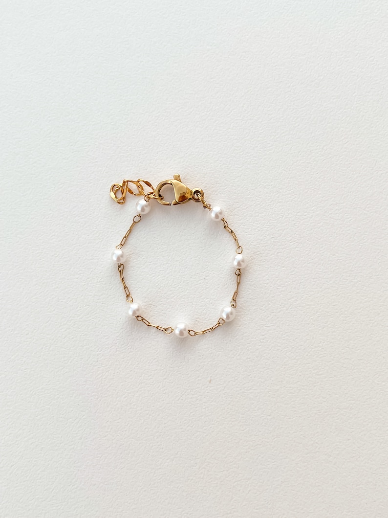 May include: A delicate gold chain bracelet with small white pearls.