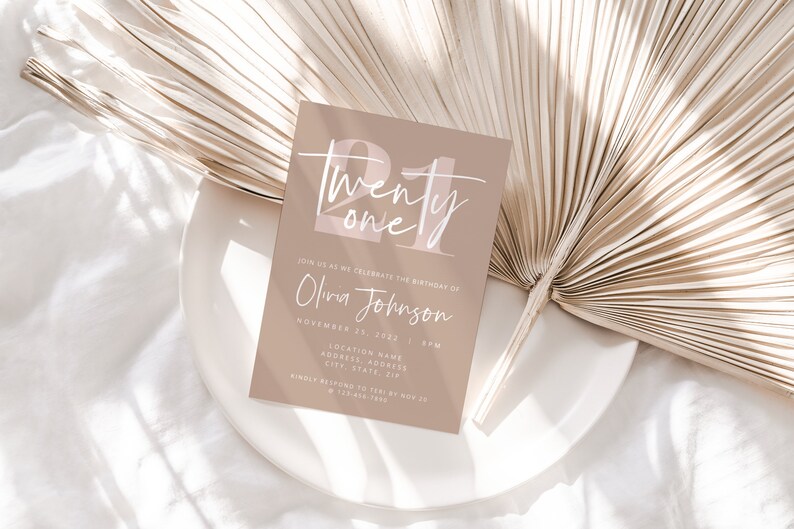 May include: A beige invitation card with the text "Twenty one" in white script with a pink background. The text "Join us as we celebrate the birthday of Olivia Johnson" is printed below the number. The date and time of the event are listed below the name.