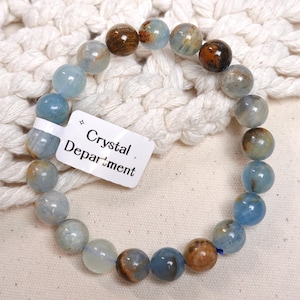 May include: A blue and brown gemstone bracelet with a white tag that reads "Crystal Department".