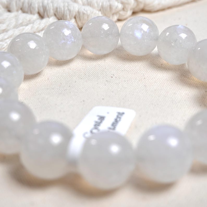 May include: A white gemstone bracelet with a tag that reads "Crystal - Crescent".