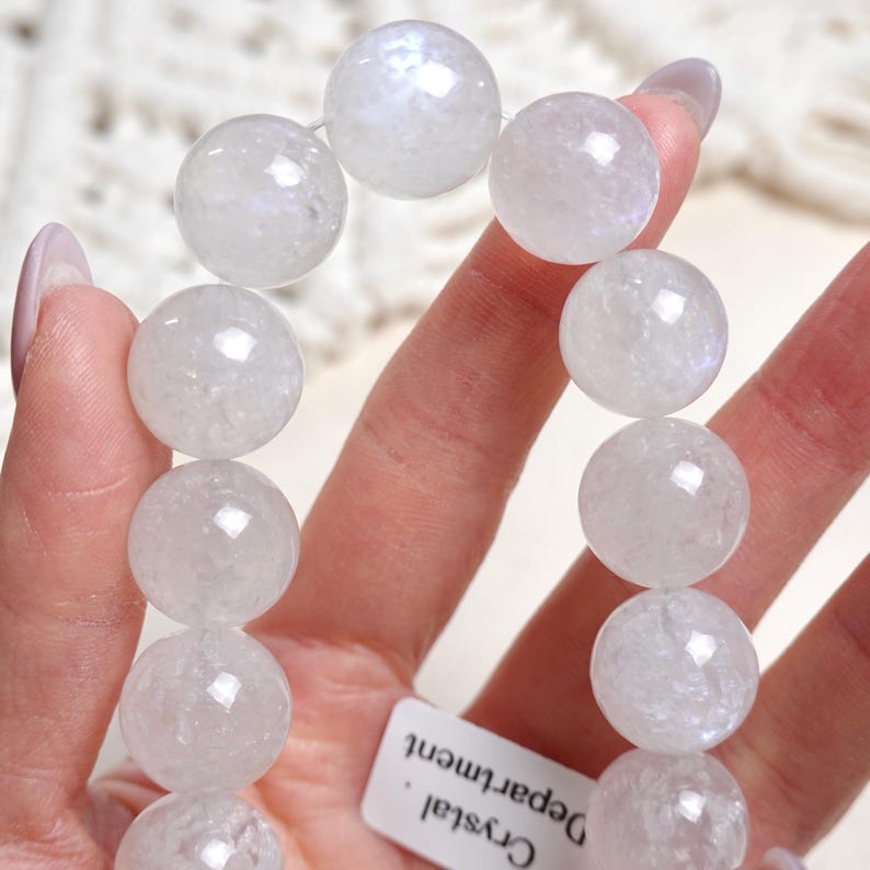 May include: White moonstone beaded bracelet with a frosted finish. The bracelet is made with round beads and is approximately 7 inches in length.