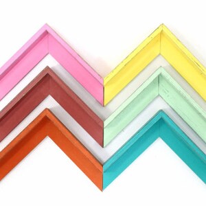 May include: Six wooden picture frames in various colors, arranged in a chevron pattern. The frames are painted in shades of pink, red, orange, green, blue, and yellow.