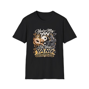 Könnte beinhalten: Ein schwarzes Kurzarm-T-Shirt mit einem Grafikdruck eines Yin-Yang-Symbols, flankiert von zwei verzierten Maskenballmasken in Gold und Schwarz. Der Text lautet: You're My YIN I'm Your YANG Remember It, umgeben von kleinen goldenen und silbernen Herzumrissen.