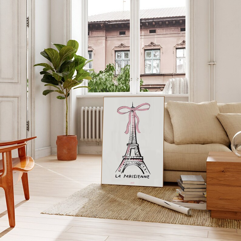 May include: A white framed print with a black and white illustration of the Eiffel Tower with a pink bow on top. The text "LA PARISIENNE" is below the tower.