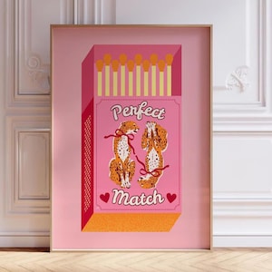 Puede incluir: Una caja de cerillas rosa y naranja con dos animales de estampado de guepardo en su interior. La caja dice "Perfect Match" con corazones a cada lado del texto.