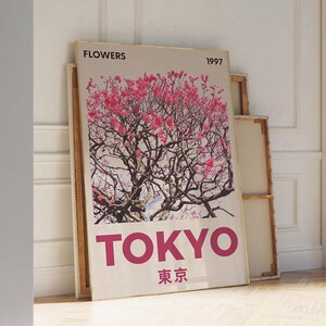 May include: A framed art print featuring a pink flowering tree against a light background. The word "FLOWERS" is at the top, with "1997" next to it. The word "TOKYO" is in large pink letters, with Japanese characters below.